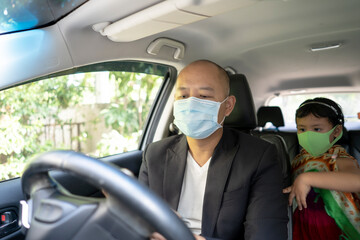 Young father sitting in car with daughter wearing healthy face mask.