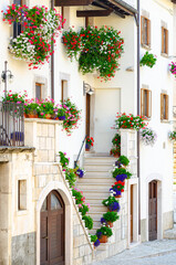 Fototapeta na wymiar Pescocostanzo, Italy. August 24th, 2012. Facades of historic buildings decorated with plants and flower pots of different colors in Strada di S. Francesco street.