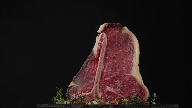 T bone. Raw beef steak. Presentation of the dish. Rotation. Black background.