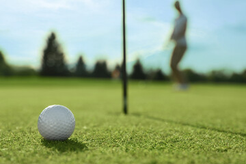 Woman playing golf at green course, focus on ball. Space for text