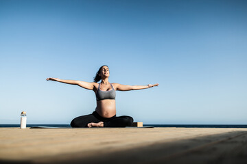 Fototapeta na wymiar Young pregnant woman doing yoga outdoor at the beach - Focus on face