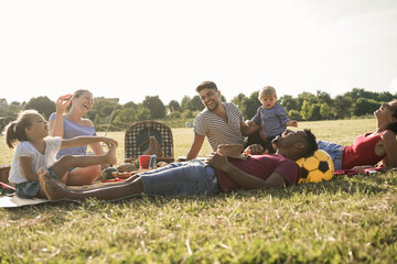 Happy multiracial families doing picnic outdoor in city park during summer vacation - Main focus child boy