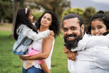 Happy indian family having fun outdoor at city park - Main focus on father face