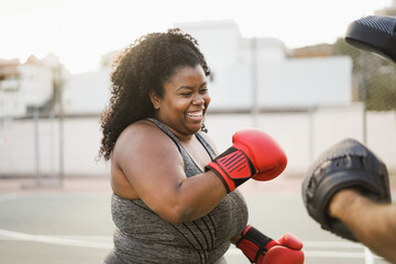 African curvy girl and personal trainer doing boxing workout session outdoor with her personal trainer - Focus on face - Powered by Adobe