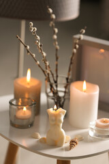 Fototapeta na wymiar Beautiful body shaped candles and willow bouquet on table indoors