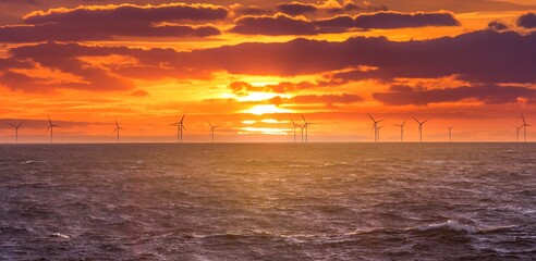 Renewable green electricity wind power generation offshore. Sunrise at decarbonization industry...