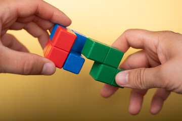 Hand holding piece of wooden block puzzle. wood cube stacking. Concept of complex and smart logical thinking. Slightly defocused and close up shot. on ... Mehr anzeigen.