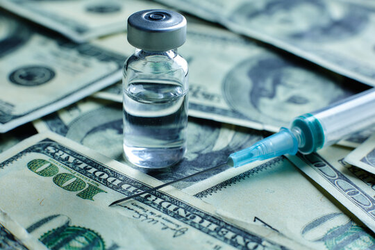 Vaccine vial and syringe on the background of one hundred dollar bills