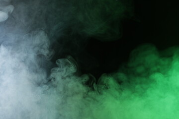Artificial smoke in grey-green light on black background