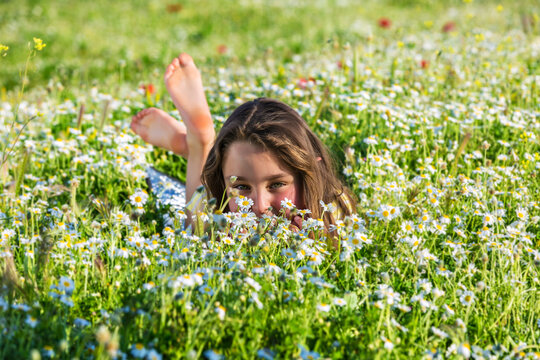 Charming little girl lying amidst blooming meadow