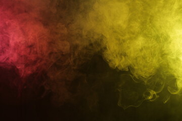Naklejka na ściany i meble Artificial magic smoke in red-yellow light on black background
