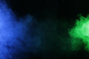 Artificial magic smoke in blue green light on black background