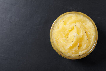 Body scrub in glass bowl on black table, top view. Space for text