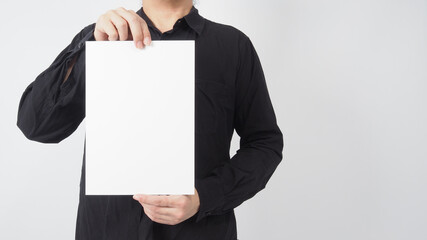 Empty space for text.Male asian wear black shirt and hand is holding blank paper board on white background.