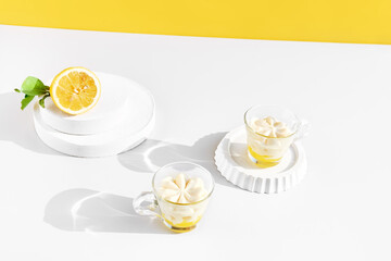 Lemon mousse or ice cream in a glass cups on yellow background. Traditional Italian recipe of lemon tiramisu or granita. Delicious summer dessert.