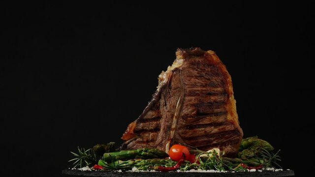 T bone beef steak, grilled. Presentation of the dish. Rotation. Black background.