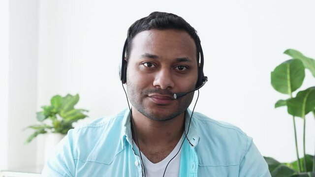Headshot of a young Indian man in a headset looking at the camera listening attentively to the interlocutor, online meeting, support officer, video chat, call