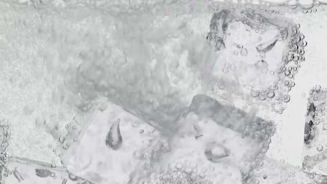 Einschenken von frischem Mineralwasser mit Eisw&uuml;rfel im Gegenlicht