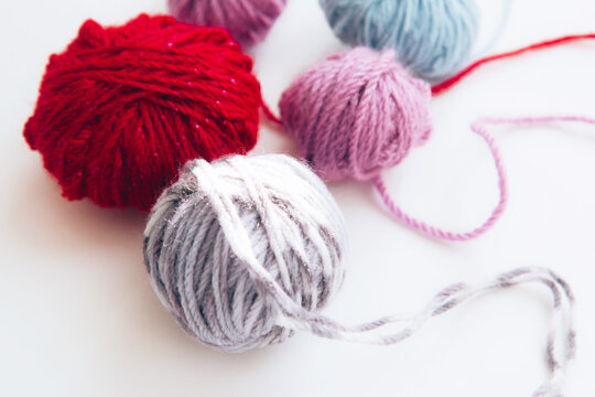 Multicolored skeins of multi-colored woolen yarn on light background with copy space. Close up