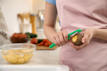 Obraz na płótnie Canvas Woman peeling potato in kitchen, closeup. Preparing vegetable