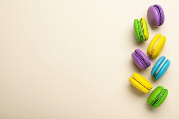 Delicious colorful macarons on beige background, flat lay. Space for text