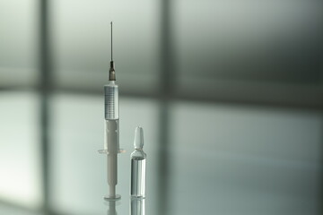Medicine vial and syringe on glass table in clinic room