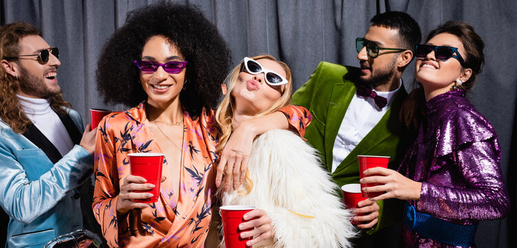 playful interracial friends in sunglasses on grey background, banner.