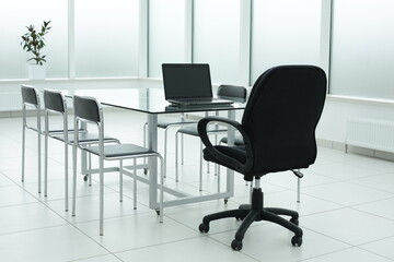 Laptop on glass table in spacious office space