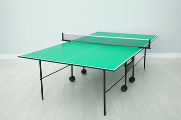 One green ping pong table with net indoors