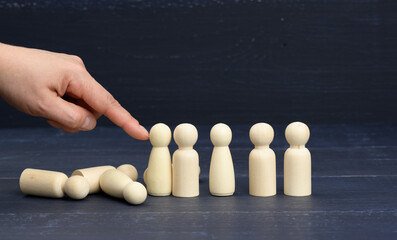 hand pushes the wooden figures of men, they fall in different directions. The concept of...