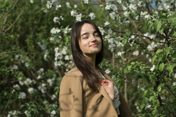 Portrait of a positive cheerful brunette girl in a green spring park