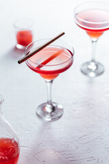 Cosmopolitan cocktail served with lemon wedges on a white background