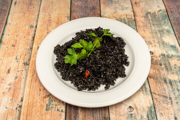 Portion of Spanish black paella with parsley on top to serve as tapas