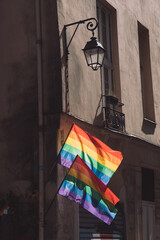 Transgender Pride flags. Lgbtq flags hanging at historic building corner during Paris pride. LGBTQIA culture symbol. Vintage lantern streetlight and bright gay flags waving in wind at sunny day