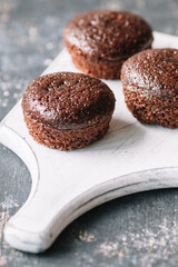 Chocolate muffins with and without cream on a dark background