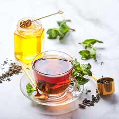 Black tea in glass transparent mug with mint leaves and honey. Calming and revitalizing tea, anti-stress and relaxation