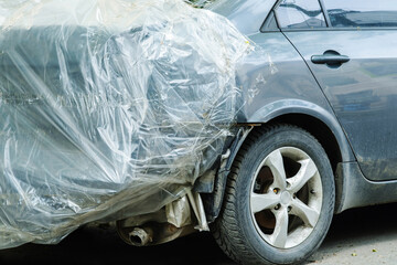The wrecked car in the accident is covered with a plastic film. The back of the car. Close-up