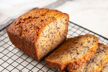 Sliced loaf of banana bread cupcake with poppy seeds on cooling wrack