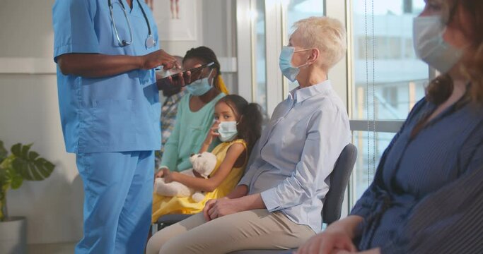 Diverse patients in safety mask sitting in queue for covid-19 vaccination at hospital