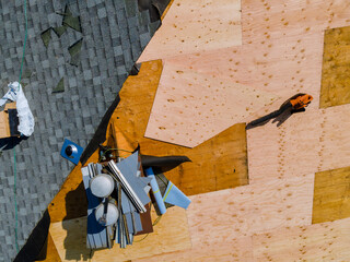 A worker replace shingles on the roof of a home repairing the roof of home