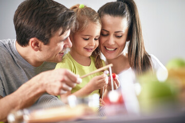 Mom and Dad playing with their little daughter during a breakfast at home. Family, breakfast, playing, togetherness
