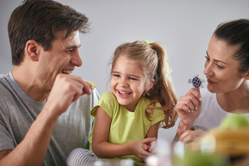 A young parents having a good time with their daughter after a breakfast at dining room. Family, together, breakfast, home