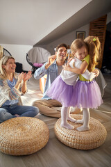 Little sisters are hugging while having a good time with their parents at home. Family, together,...