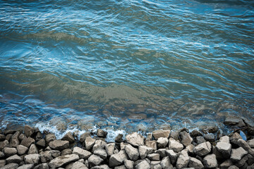 Ufer mit Steinen an einem Fluss oder Meer mit Wellen