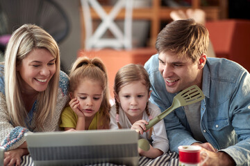 Obraz premium A young family watching a laptop content on the bed at home together. Family, together, love, home