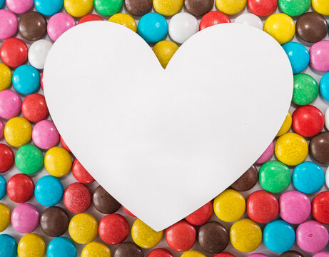 white heart on a background of round colored sweets.