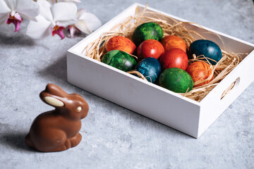Easter eggs in box with golden hay on a rustic plain grey background