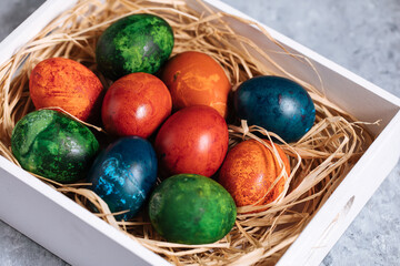 Easter eggs in box with golden hay on a rustic plain grey background