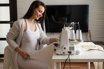 Caucasian woman sews to order at home. Work space of a seamstress in the living room