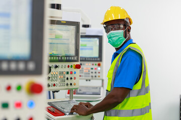 Portrait of African black man worker wearing protective face mask standing in front of control panel machine at the steel factory. Young African man in safety uniform with smiley face